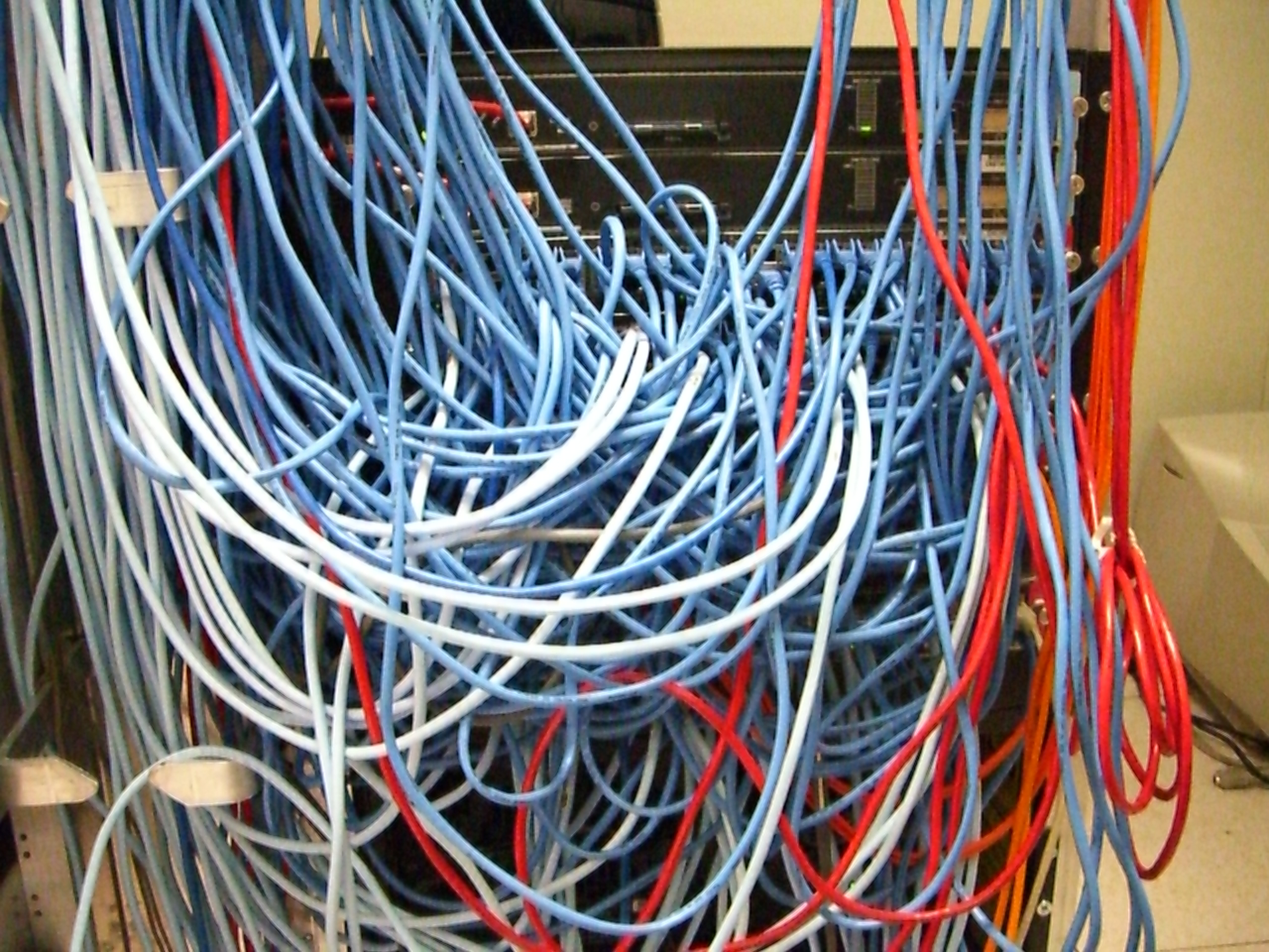 Serverrack mit chaotischer Verkabelung als Symbolbild für komplexe und angreifbare Enterprise-Infrastruktur. Bildquelle: Kim Scarborough / Wikimedia Commons, CC BY-SA 2.0.