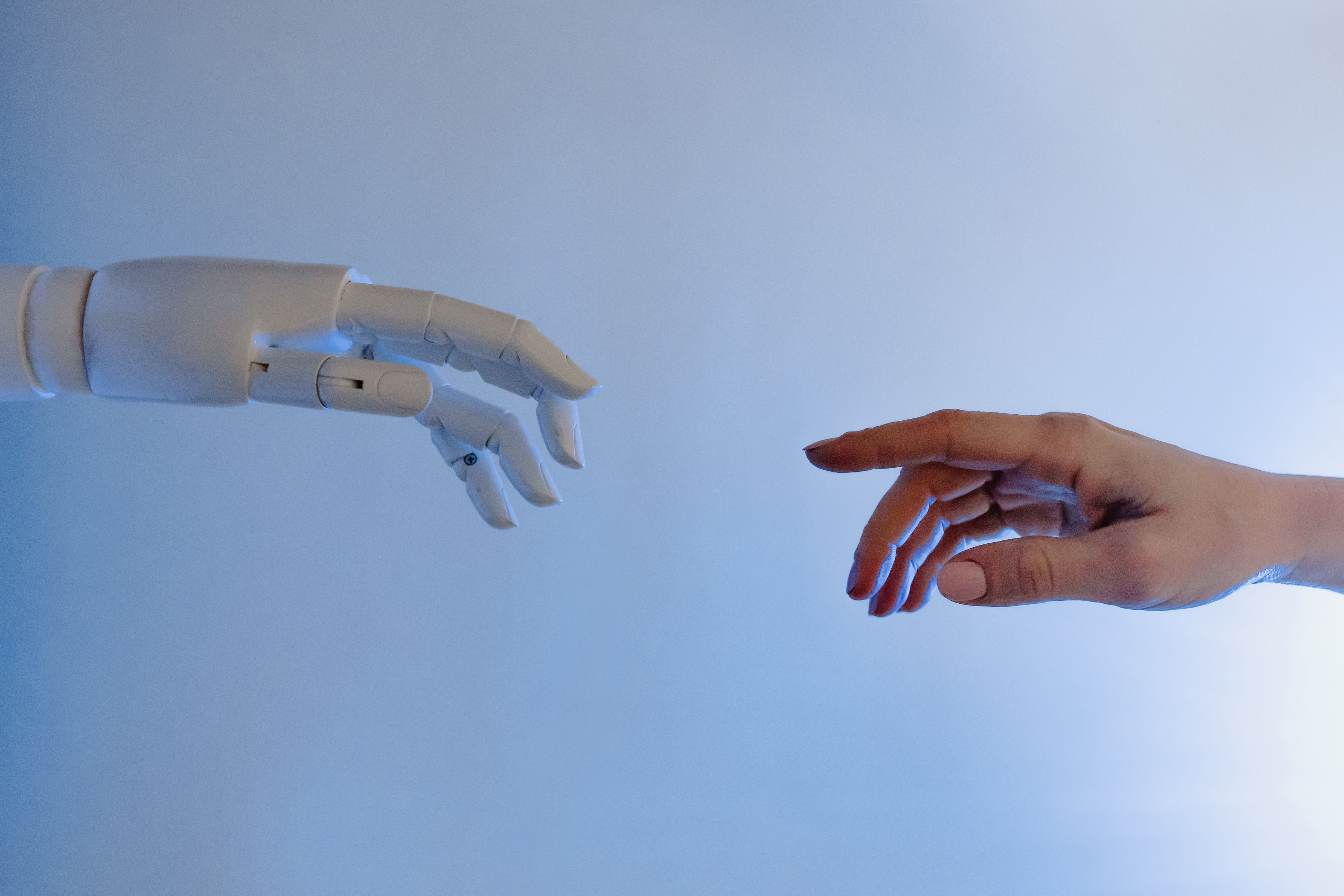Eine menschliche Hand und eine Roboterhand reichen sich entgegen – Metapher für die Zusammenarbeit von Mensch und KI (Tara Winstead via Pexels)
